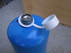 a blue propane gas tank with a white cap on the top and a metal spigot sticking out of it