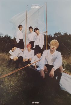 a group of young men sitting next to each other on top of a grass covered field