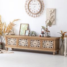 a large clock mounted to the side of a wall next to plants and potted plants