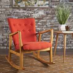 an orange rocking chair next to a small table with a potted plant on it