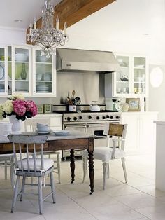 a kitchen with white cabinets and an old fashioned table in the center, surrounded by chairs