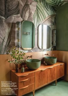 a bathroom with two green bowls on the vanity and mirror above it is decorated with palm leaves