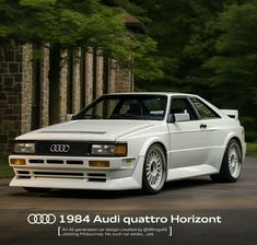 an audi quattro is parked in front of a house with trees behind it