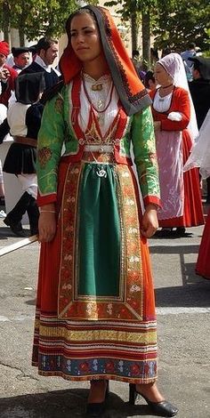 a woman in an ethnic dress is standing on the street with other people behind her