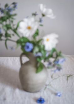 a white vase filled with blue and white flowers