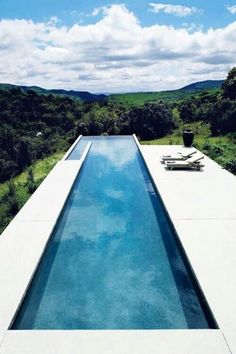 an empty swimming pool in the middle of a lush green field with trees and bushes