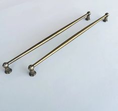 two brass colored handles and knobs on a white surface