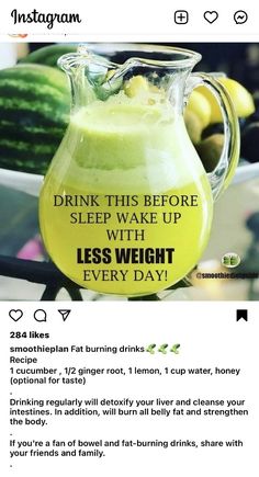 a glass pitcher filled with liquid sitting on top of a table next to cucumbers