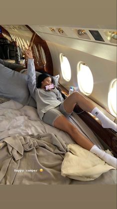 a woman laying on top of a bed in an airplane