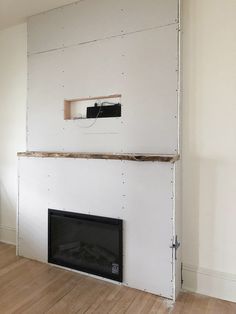 an empty room with a fire place in the middle and a wall mounted tv above it