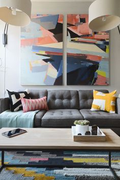 a living room with two paintings on the wall and a coffee table in front of it