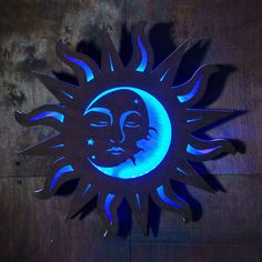 a metal sun and moon with blue lights on the face is shown against a dark wood background