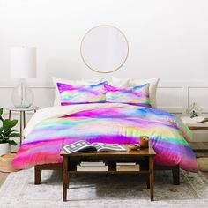 a bed with a colorful comforter and pillows on top of it in a room