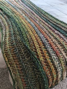 a multicolored crocheted blanket sitting on top of a bed