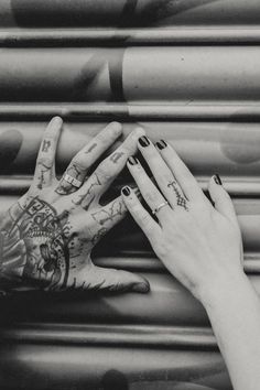 black and white photograph of two hands reaching for each other with tattoos on their arms