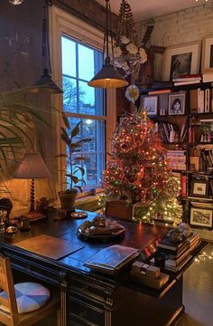 a christmas tree is lit up in the corner of a room next to a window