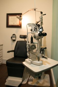 an eye doctor's chair in the middle of a room with two microscopes on it