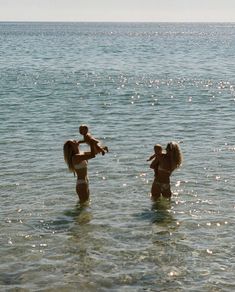 two women and a child are in the water with their arms around each other as they play