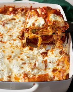 a white casserole dish filled with lasagna sauce and cheese being lifted from the casserole