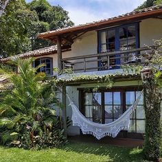 a house with a hammock in front of it and lots of greenery