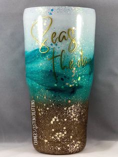 a glass with gold and blue paint on it that says, seas the day written in cursive writing