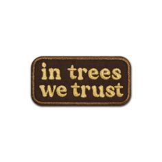 the words in trees we trust are embroidered on a brown and beige patch with gold lettering