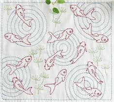 a white table cloth with red and green embroidered designs on it, including two birds