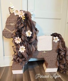 a horse made out of brown paper with flowers on it's head and tail