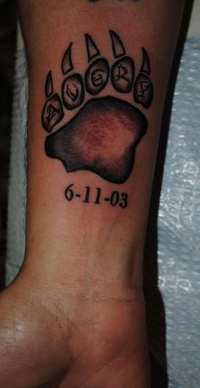 a tattoo on the wrist of a person with a dog paw and number 6 in it