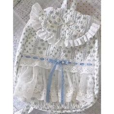 two pieces of white lace with blue bows on them and one piece has ruffles