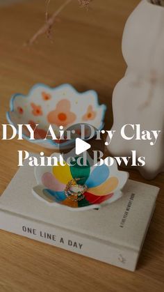 a book and bowl on a table with the title diy air dry clay painted bowls