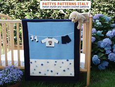 a baby crib with a teddy bear hanging from it's clothes line and blue flowers in the background