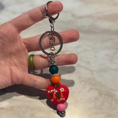 a hand holding a keychain with a heart on it