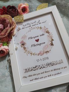 a framed wedding card with flowers on the table