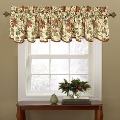 a window with a flowered valance on it and a potted plant next to the window