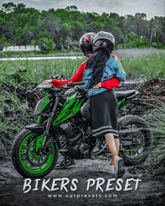 two people sitting on a green motorcycle in the mud with trees and grass behind them