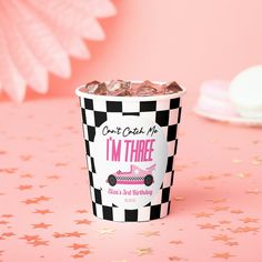 a pink and black checkered paper cup with candy in it on a pink table