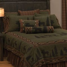 a bed with green comforter and pillows on top of it next to a night stand