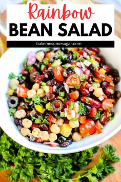 rainbow bean salad in a white bowl with cilantro and parsley on the side