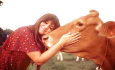 a girl is hugging a cow in a field