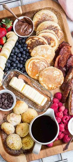 a wooden platter filled with different types of breakfast foods and fruit on top of it