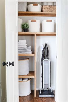 a vacuum is sitting on the floor in front of an open closet with white bins