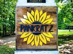 a wooden sign with the word pankratz on it in front of some trees