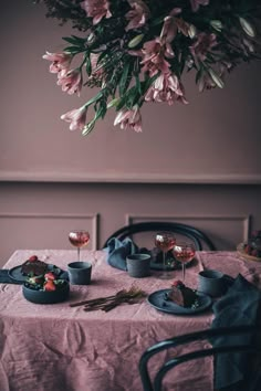 a table topped with plates and cups filled with food next to a flower hanging from the ceiling