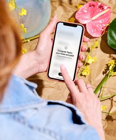 a woman is looking at her cell phone while sitting on the ground next to flowers