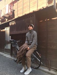 a man sitting on the back of a bike in front of a building with wooden doors