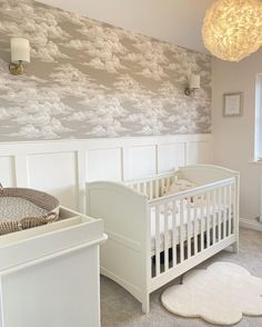 a baby's room with white furniture and wallpaper