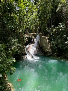 there is a waterfall in the middle of this river with green water and trees around it