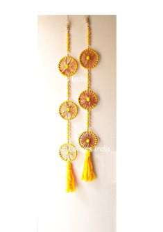 the wall hanging is decorated with yellow tassels and orange beads, along with other decorative items