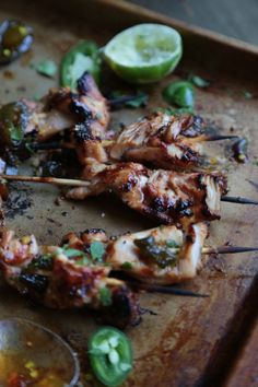 grilled chicken skewers with peppers and limes on a wooden cutting board